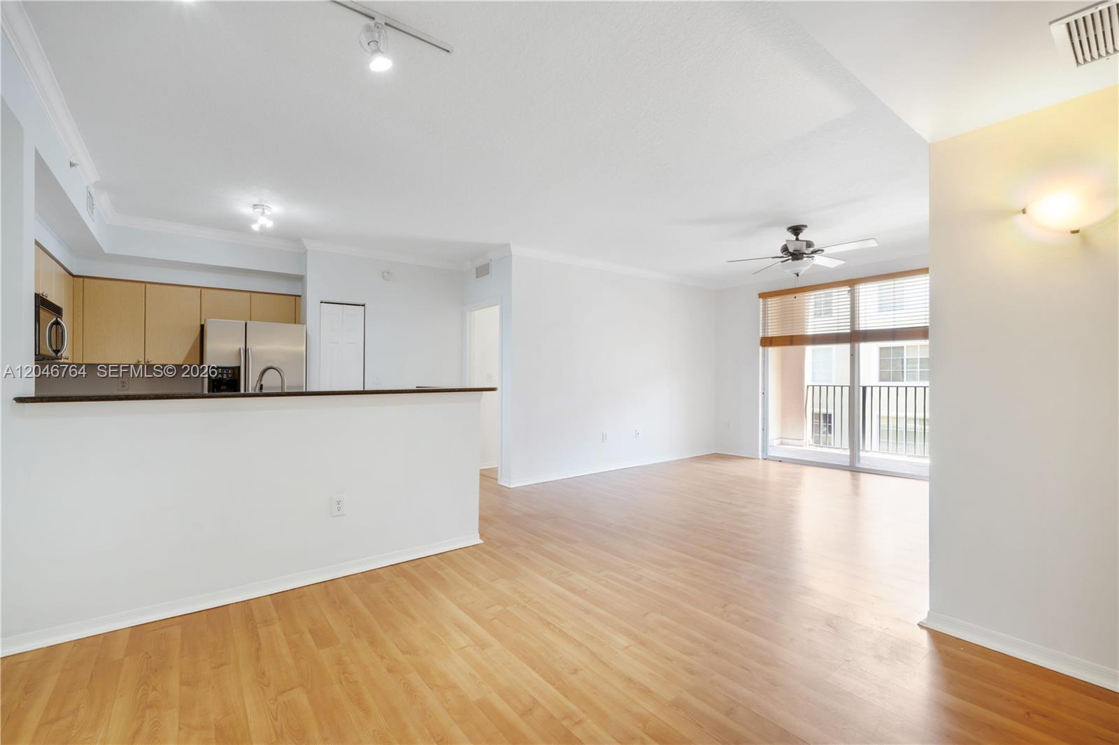 An open-concept living area features light wood flooring, a kitchen island, and a balcony — 6851 SW 44th St # 208, Miami FL 33155, MIAMI, FL