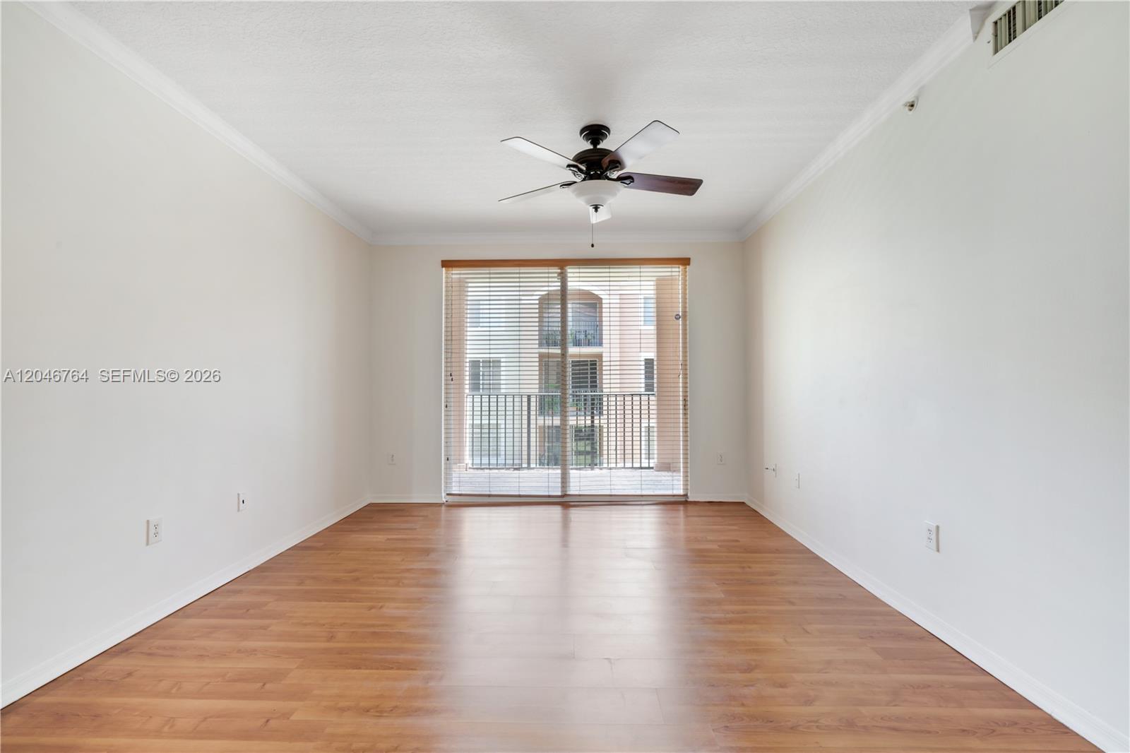An empty room features light wood-look flooring, white walls, a ceiling fan, and sliding doors — 6851 SW 44th St # 208, Miami FL 33155, MIAMI, FL
