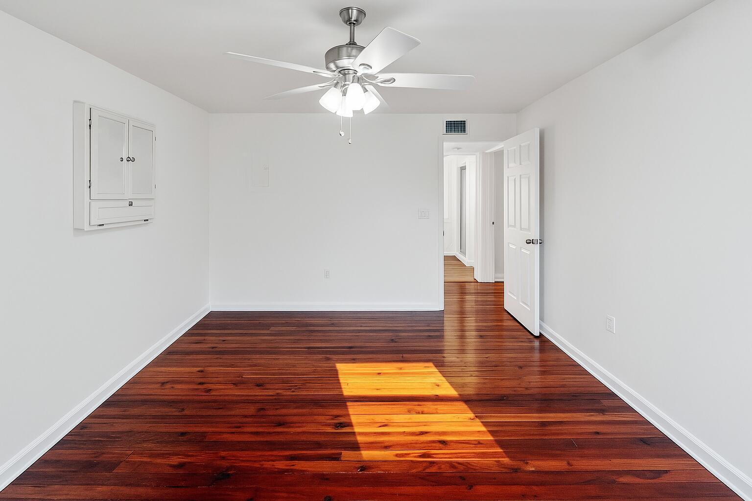 An empty room with white walls, a ceiling fan, and dark wood flooring — 415 6th Avenue N, FL 33460, FL