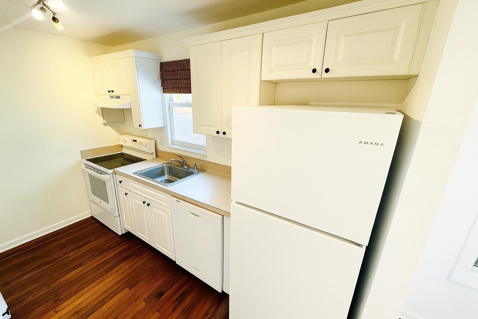 A kitchen features white cabinets, a white refrigerator, a stainless steel sink, and wood flooring — 415 6th Avenue N, FL 33460, FL