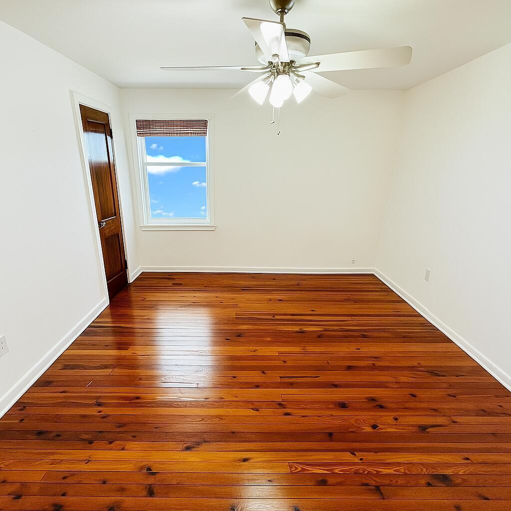 An empty room features white walls, a ceiling fan, and polished hardwood flooring — 415 6th Avenue N, FL 33460, FL
