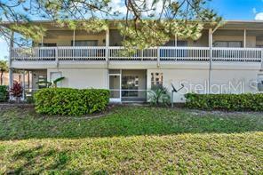 A two-story apartment building features a white exterior, a second-floor balcony, and landscaped bushes — 3204 SABAL PALMS COURT UNIT B, KISSIMMEE, FL