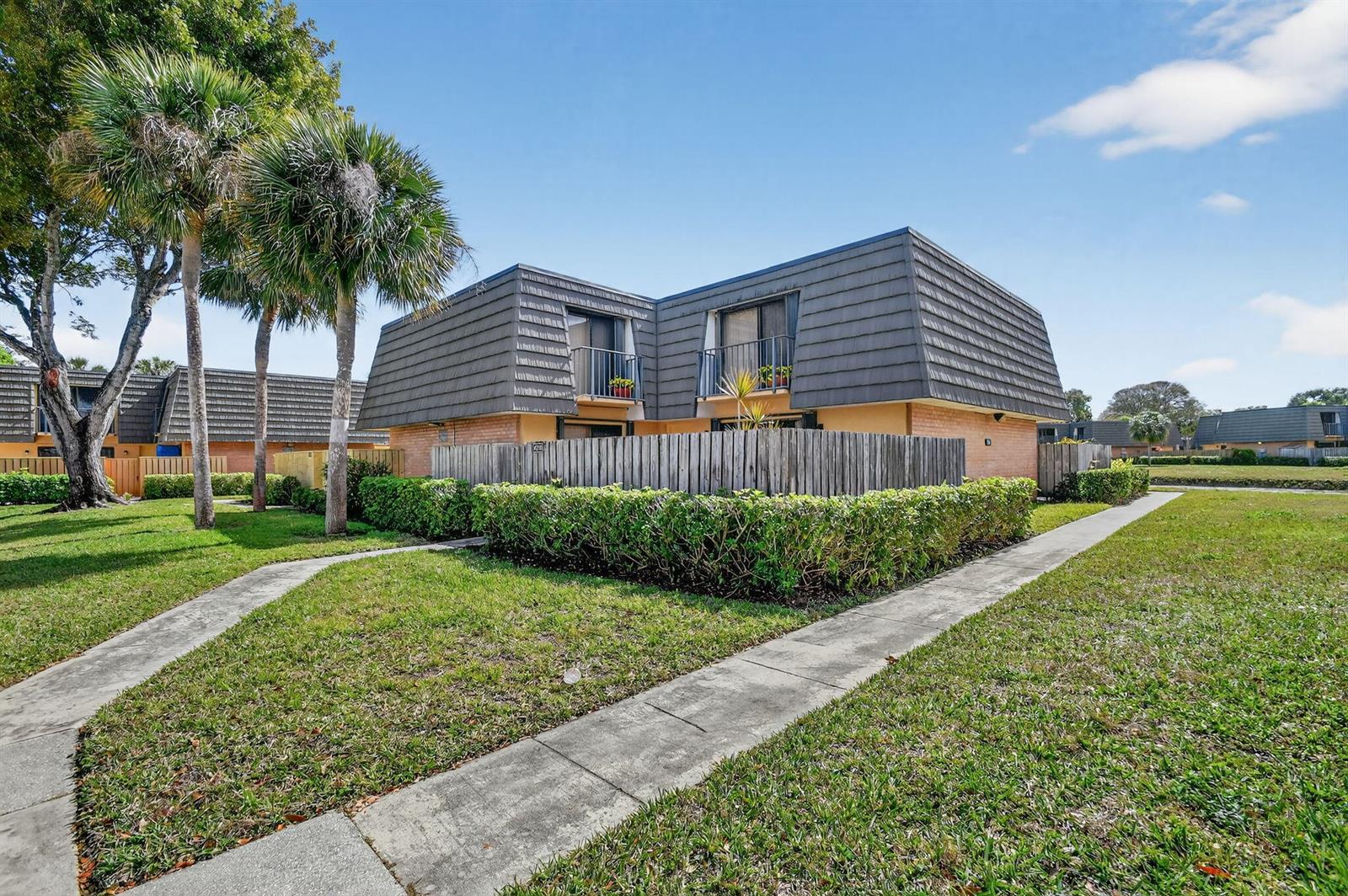 A two-story residential building with a mansard roof, balconies, and a fenced-in patio area — 4210 42nd Way, West Palm Beach FL 33407, WEST PALM BEACH, FL