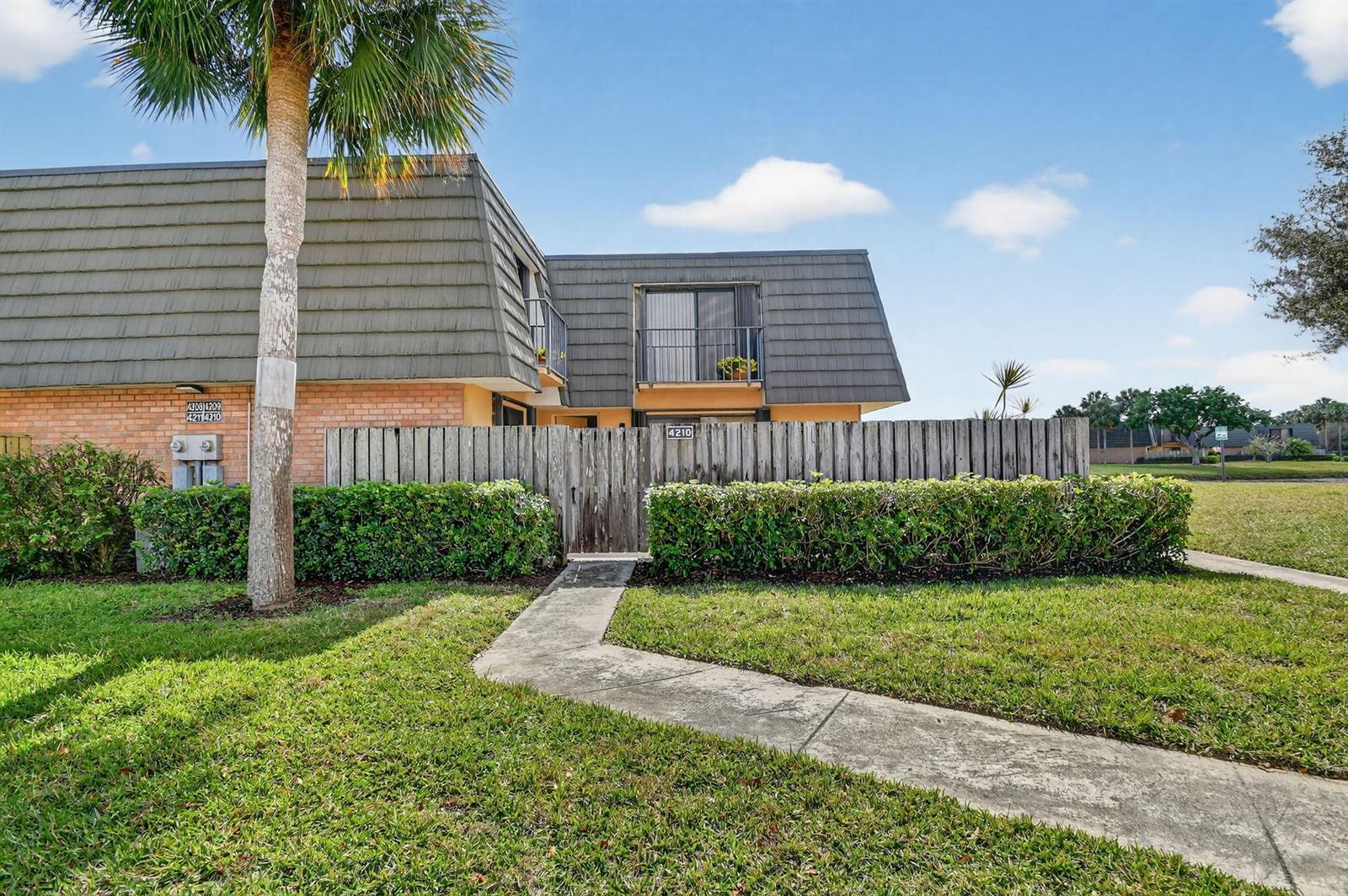 A two-story building exterior features a wooden fence, a concrete walkway, and a palm tree — 4210 42nd Way, West Palm Beach FL 33407, WEST PALM BEACH, FL