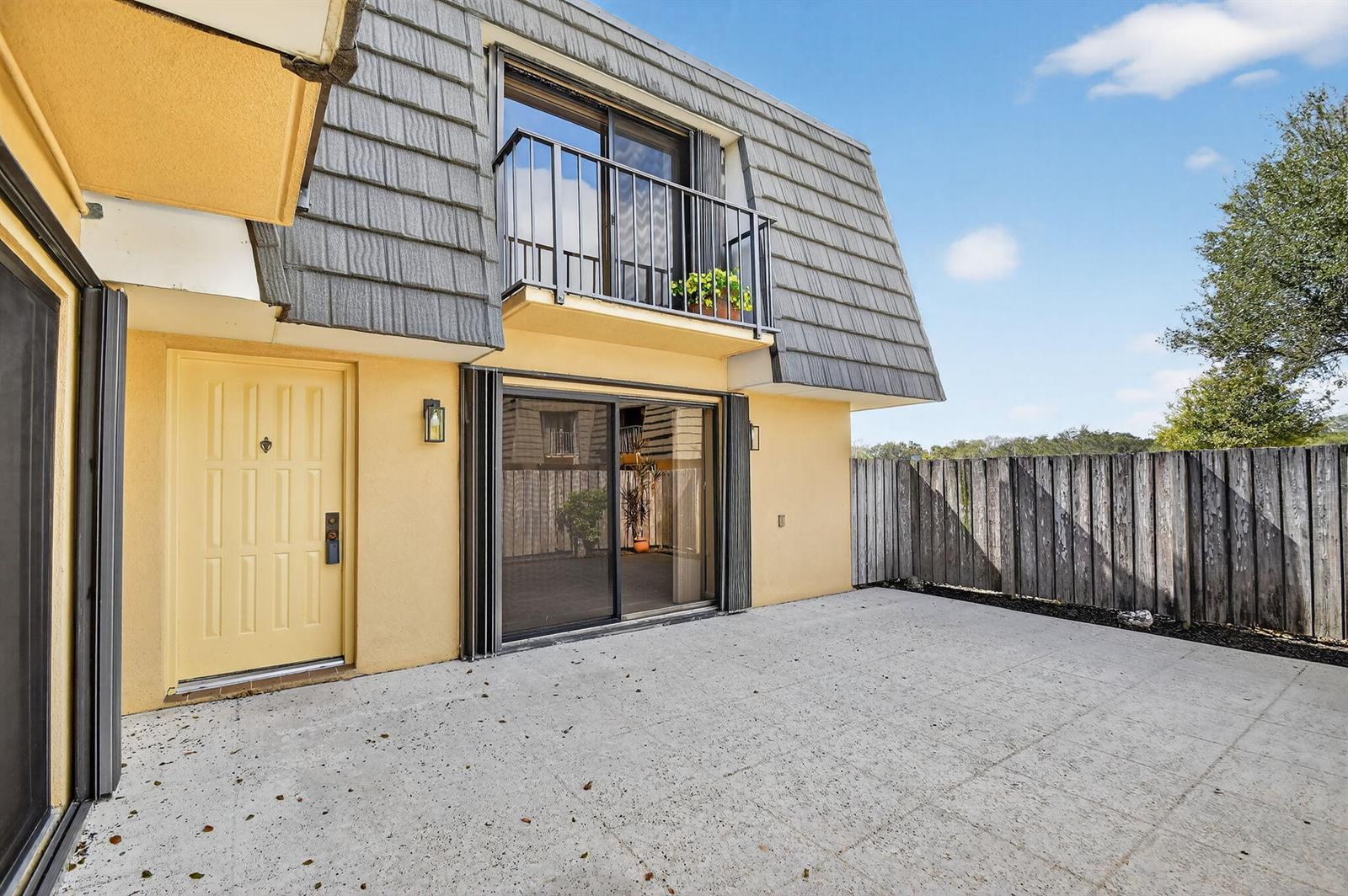 A yellow exterior wall features a front door, sliding glass doors, and an upper balcony — 4210 42nd Way, West Palm Beach FL 33407, WEST PALM BEACH, FL