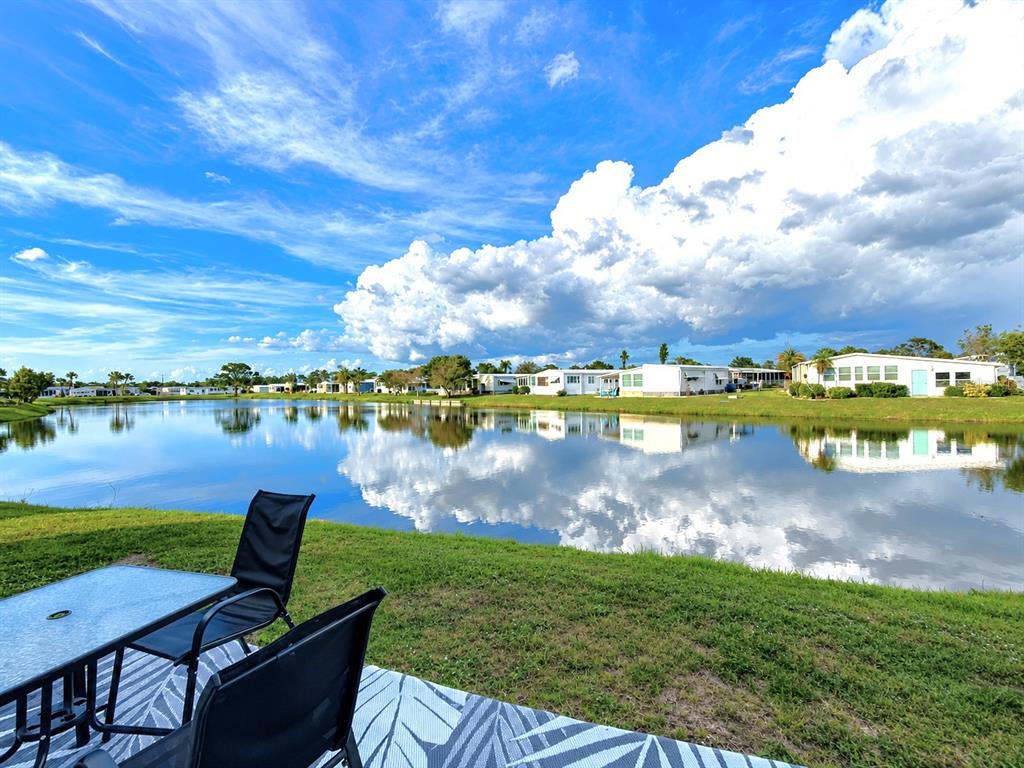 A view of a lake from a patio with outdoor furniture and mobile homes nearby — 216 MARTINIQUE ROAD, NORTH PORT, FL