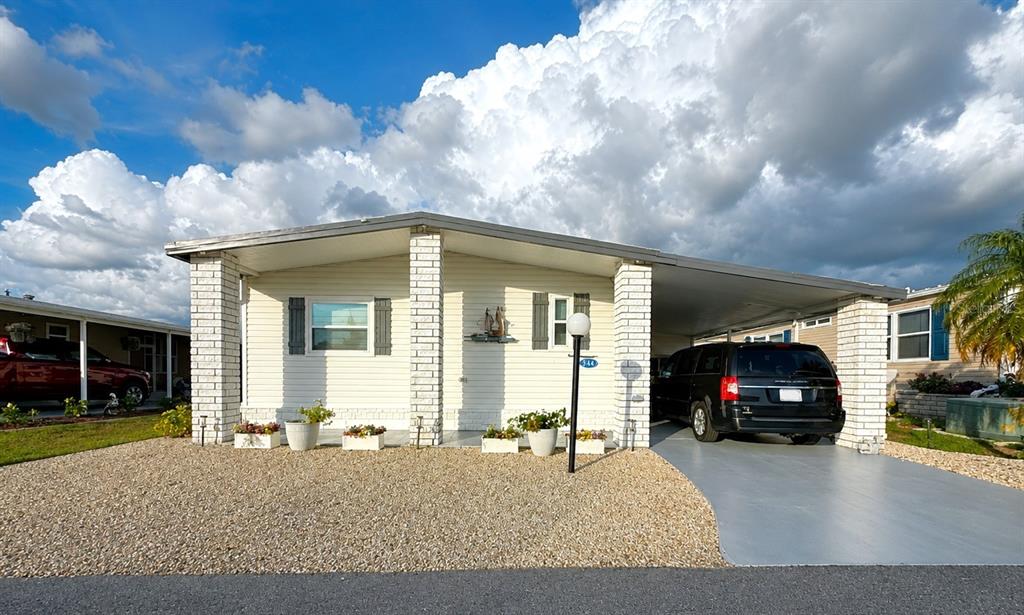 A single-story house with white siding, brick pillars, a gravel yard, and an attached carport — 216 MARTINIQUE ROAD, NORTH PORT, FL