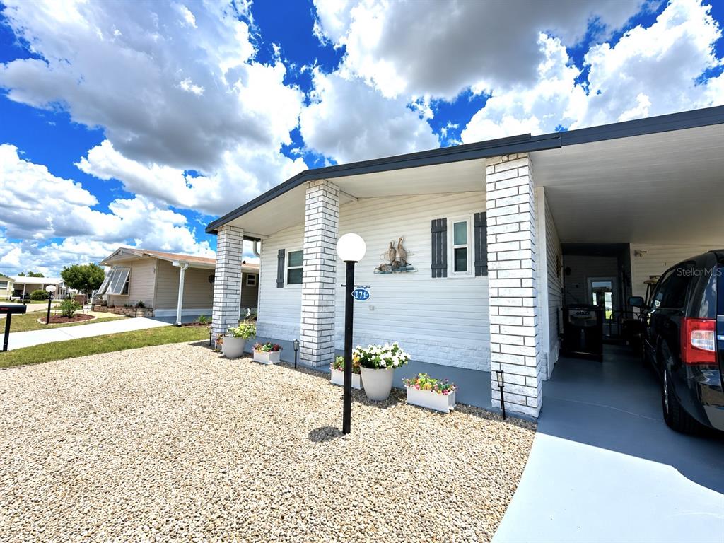 A white mobile home with a gravel front yard, brick pillars, and a carport — 216 MARTINIQUE ROAD, NORTH PORT, FL