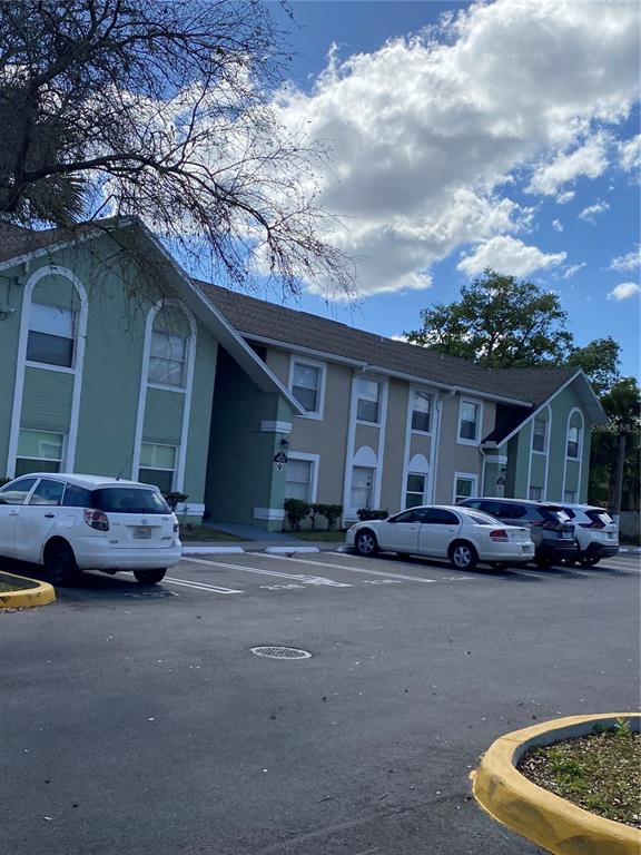 A two-story apartment building with green and tan siding sits behind a parking lot — 4252 PERSHING POINT UNIT 4, ORLANDO, FL