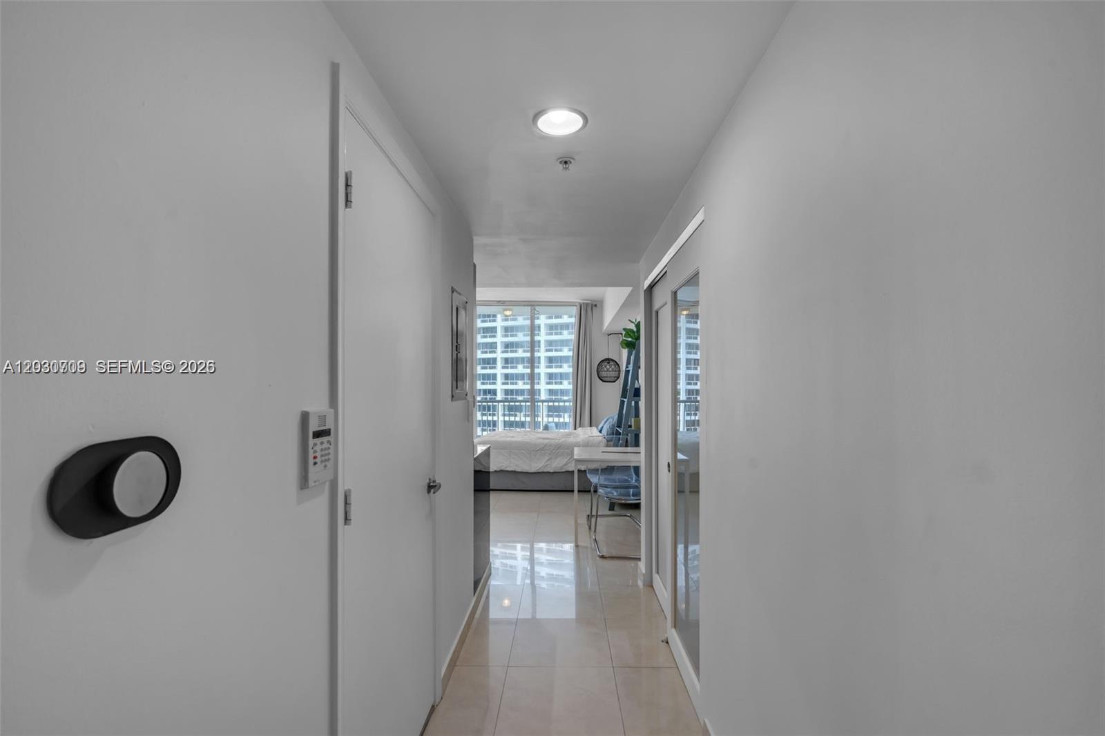 A hallway with tile flooring leads to a bedroom featuring a large window — 1750 N Bayshore Dr # 1204, Miami FL 33132, MIAMI, FL