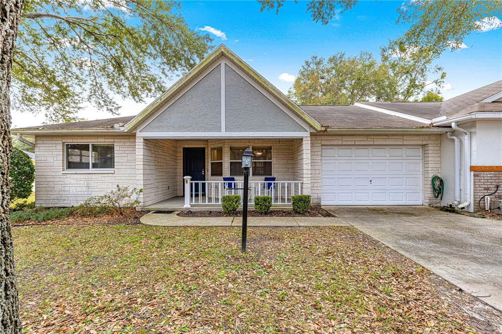 A single-story house with a white brick facade, a front porch, and an attached garage — 9662 SW 95TH COURT UNIT A, OCALA, FL