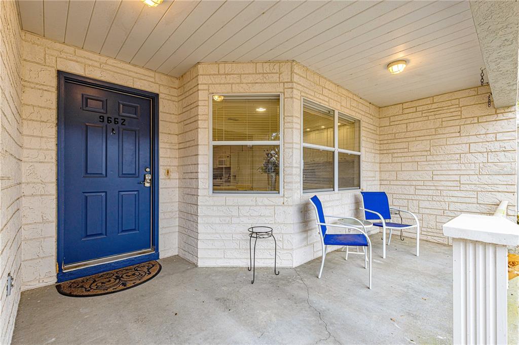 A covered front porch features a blue door, light-colored stone walls, and two blue chairs — 9662 SW 95TH COURT UNIT A, OCALA, FL