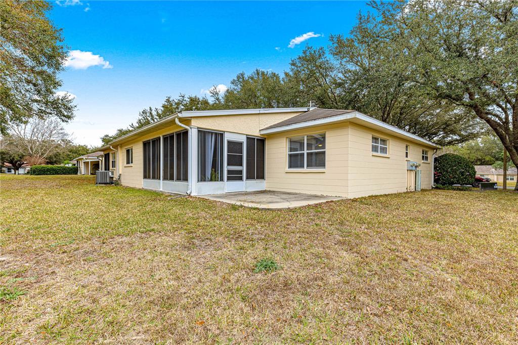 The exterior of a light yellow house features a screened-in porch and a concrete patio — 9662 SW 95TH COURT UNIT A, OCALA, FL