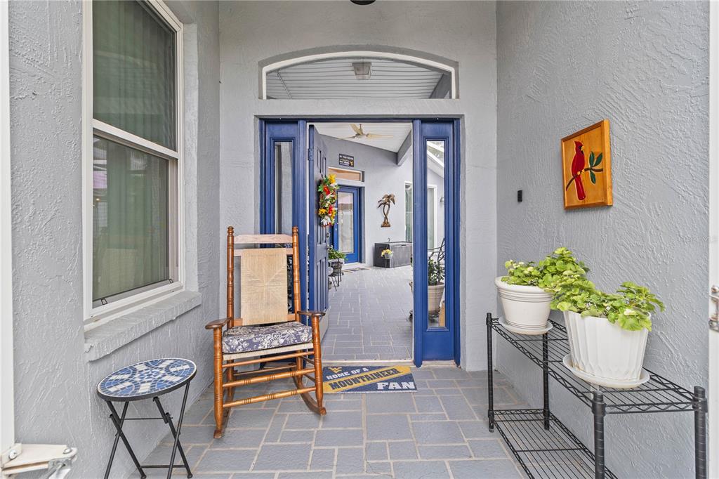 A covered entryway features a blue door, a wooden rocking chair, and potted plants — 3007 BELLFLOWER WAY, LAKELAND, FL
