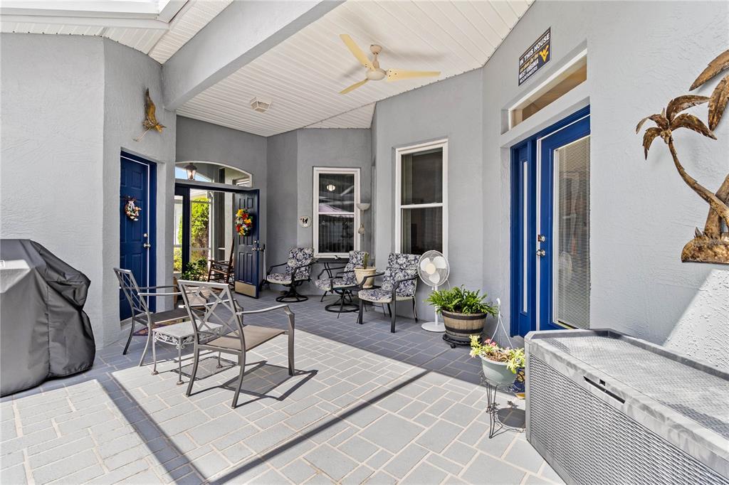 A covered patio features gray tile flooring, blue doors, and outdoor furniture — 3007 BELLFLOWER WAY, LAKELAND, FL