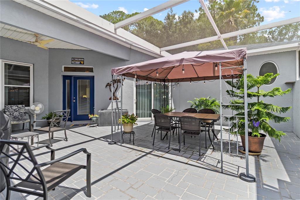 A screened-in patio features a paved floor, a dining set under a gazebo, and seating — 3007 BELLFLOWER WAY, LAKELAND, FL