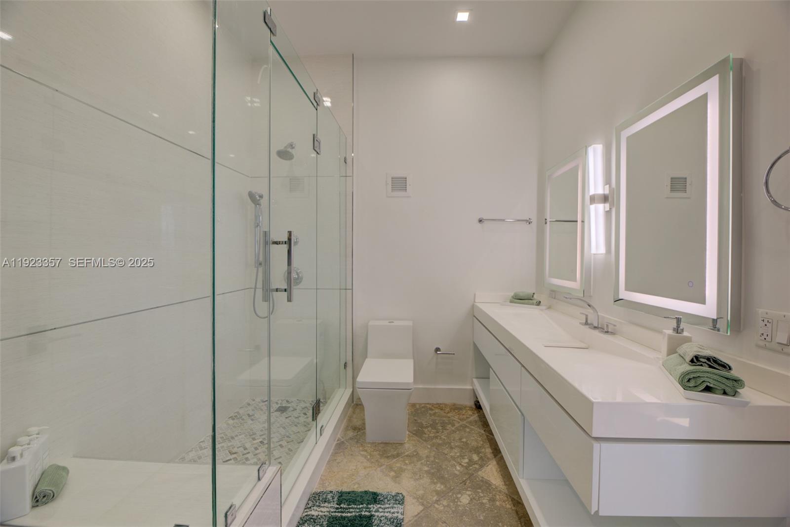 A modern bathroom features a glass-enclosed shower, a white vanity, and a toilet — 3725 S Ocean Dr, Hollywood FL 33019, HOLLYWOOD, FL