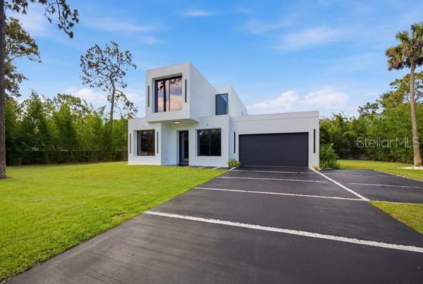A modern two-story white house with a flat roof and a large black garage door — 7412 VAN DYKE ROAD, ODESSA, FL