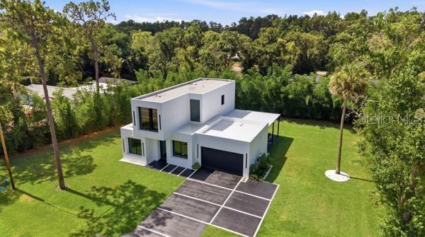 A modern kitchen features a black-and-white marble island, dark tile flooring, and a staircase — 7412 VAN DYKE ROAD, ODESSA, FL