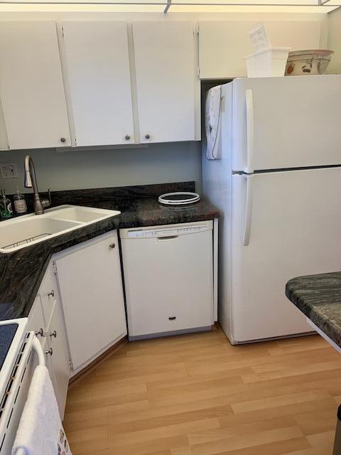 A kitchen features white cabinets, a white refrigerator, a dishwasher, and dark granite countertops — 1955 SW Palm City Road # H, Stuart FL 34994, STUART, FL
