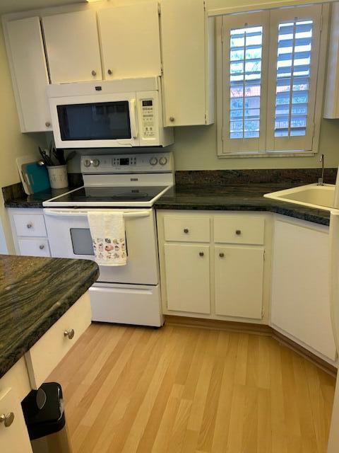A kitchen features white cabinets, a white stove and microwave, and dark granite countertops — 1955 SW Palm City Road # H, Stuart FL 34994, STUART, FL