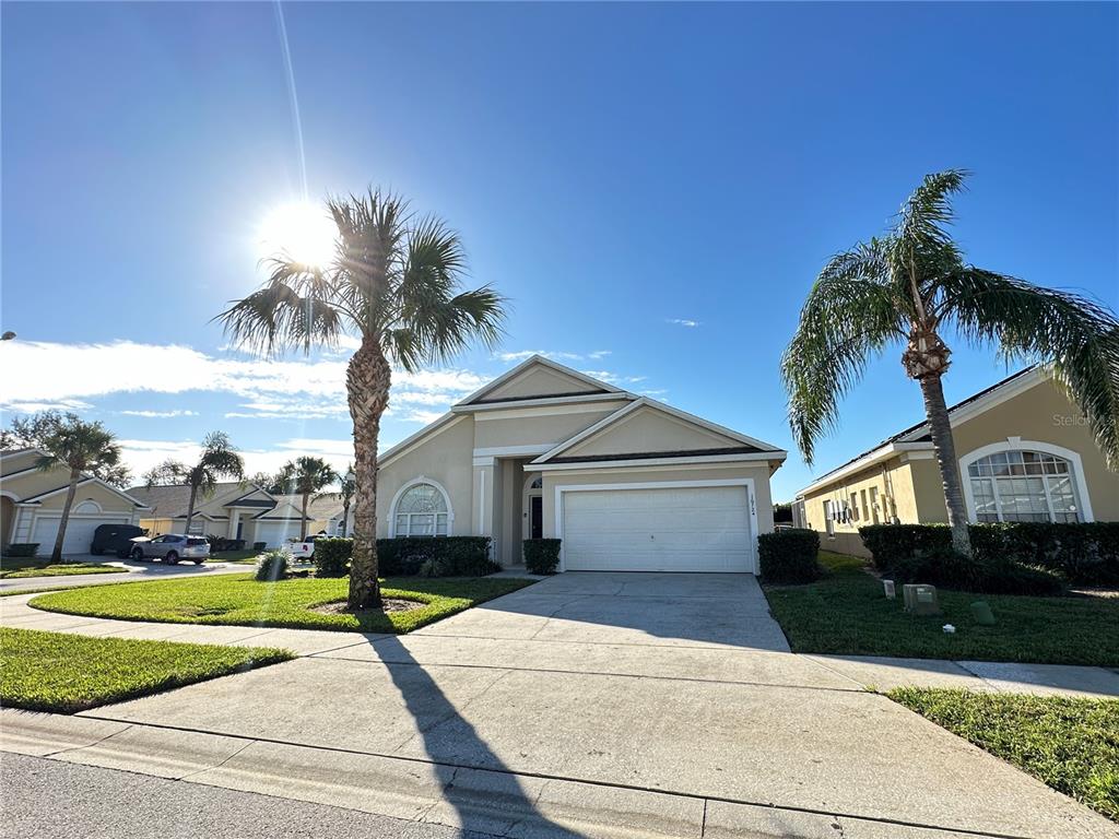 A single-story house with a two-car garage and two palm trees in the front yard — 16724 ROLLING GREEN DRIVE, CLERMONT, FL