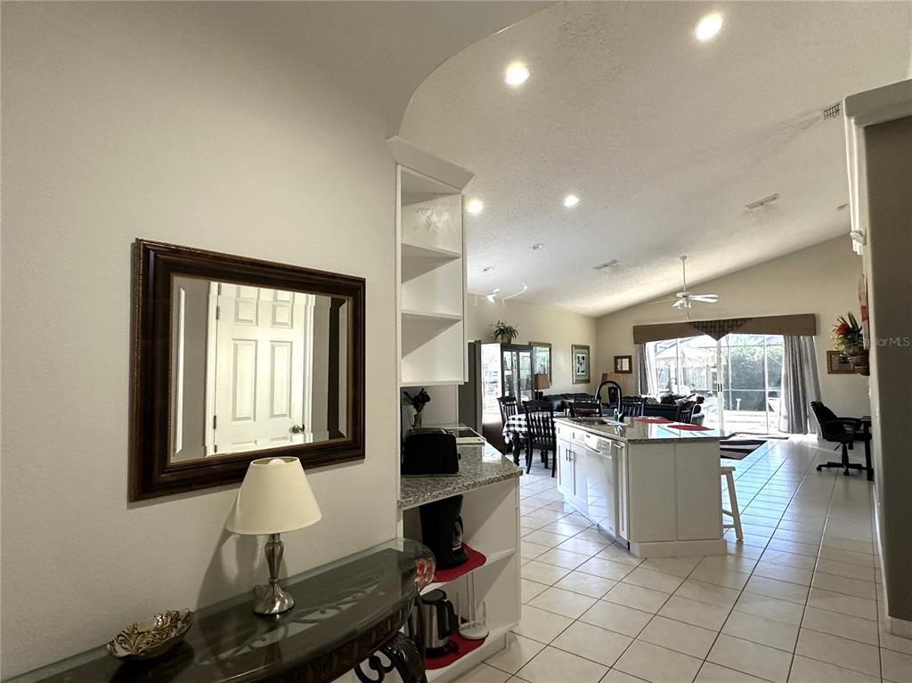 A view from a hallway into an open-concept kitchen and living area with tile floors — 16724 ROLLING GREEN DRIVE, CLERMONT, FL