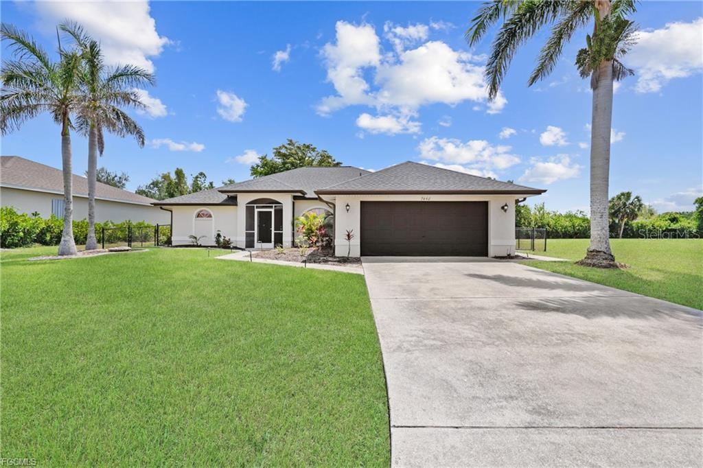 A single-story house with a beige exterior, a dark garage door, and two palm trees — 7448 S BLUE SAGE, PUNTA GORDA, FL