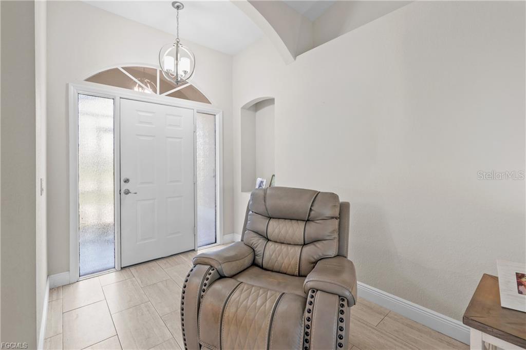 A light-filled entryway features tile flooring, a white front door, and a leather recliner — 7448 S BLUE SAGE, PUNTA GORDA, FL