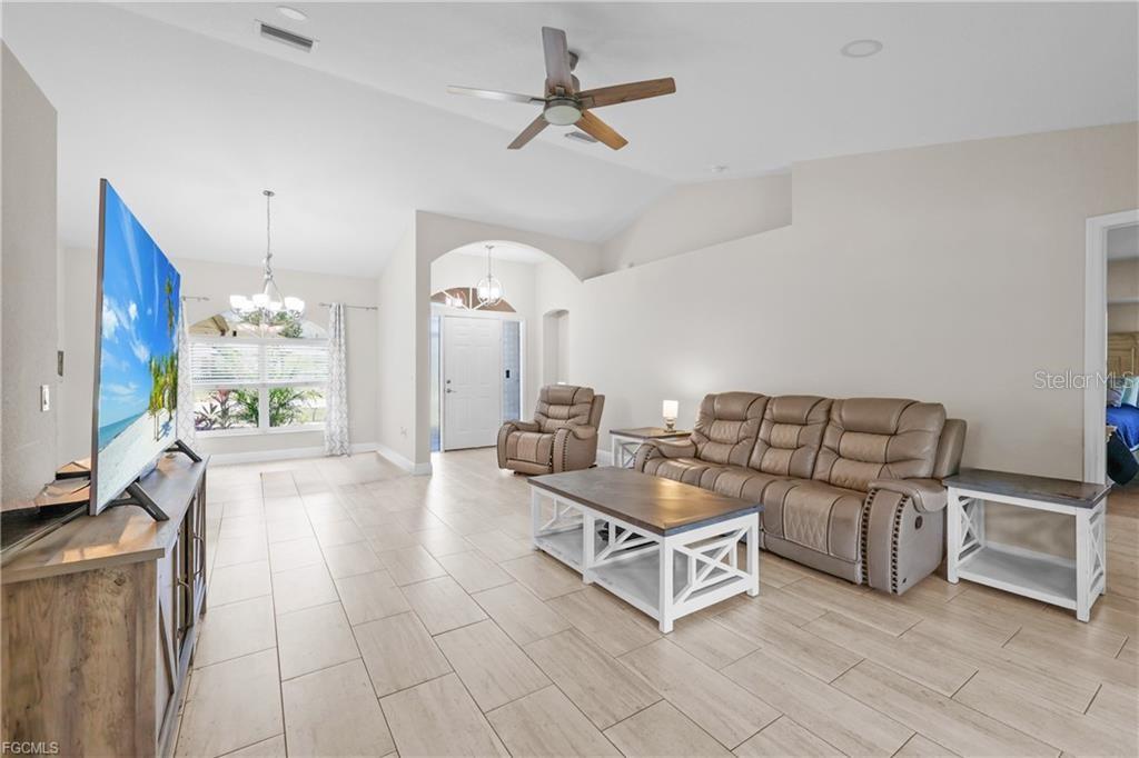 A living room features light tile flooring, a tan leather sofa, and a ceiling fan — 7448 S BLUE SAGE, PUNTA GORDA, FL