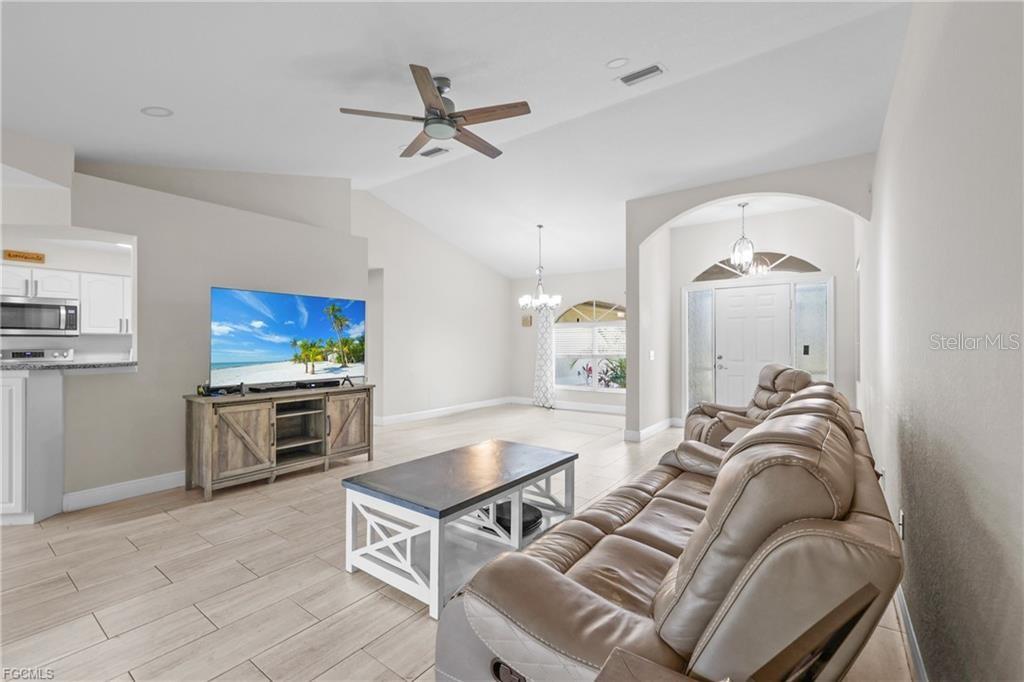 A living room features light tile floors, a tan leather sofa, and a television console — 7448 S BLUE SAGE, PUNTA GORDA, FL