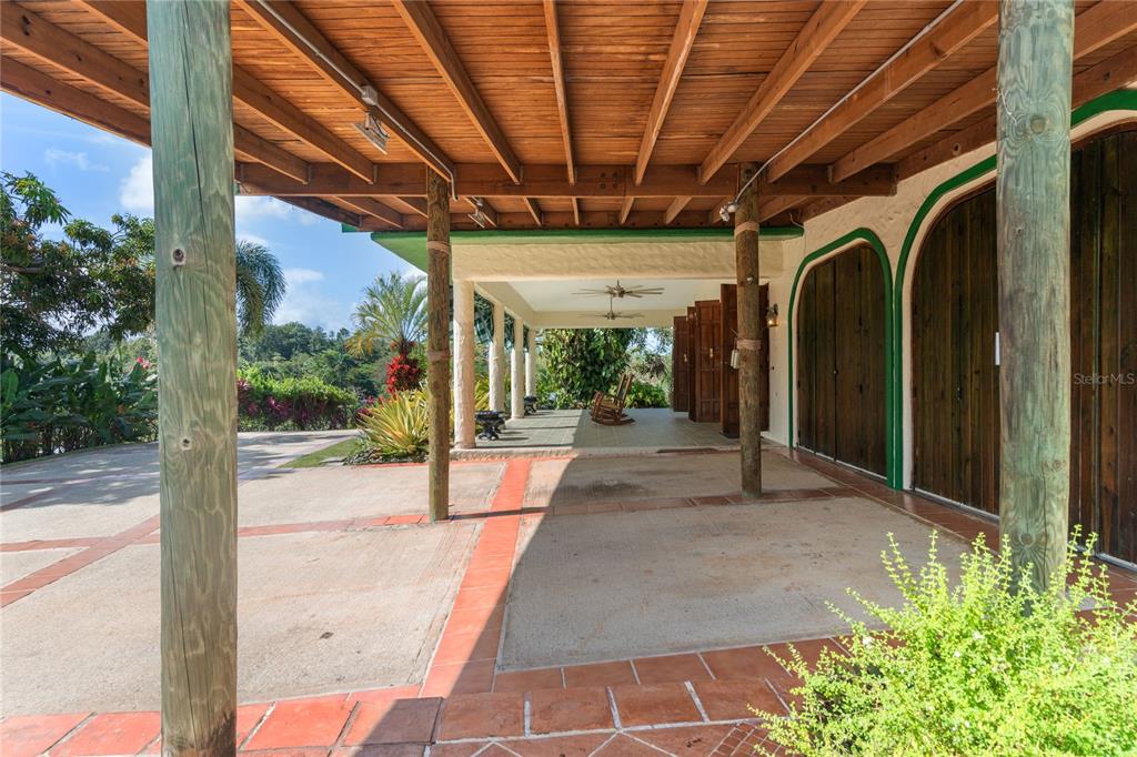 A covered patio with wooden beams, concrete flooring, and wooden support posts overlooks a landscape — 59 REINA ISABEL, RIO GRANDE, PR