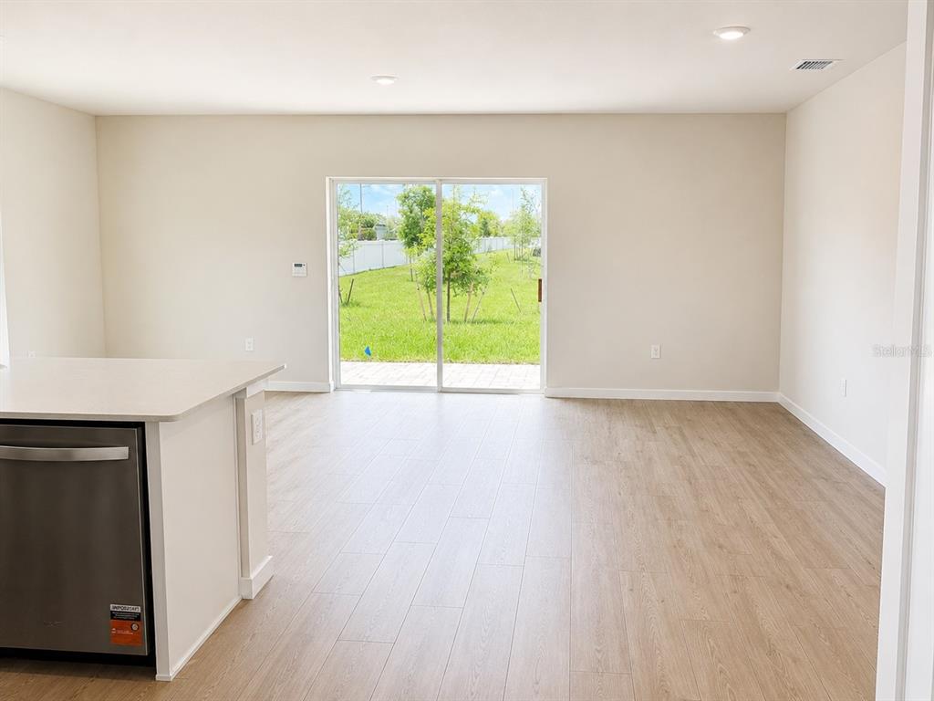 A kitchen island with a stainless steel dishwasher overlooks an open living area with sliding doors — 8201 EVERLY PRESERVE DRIVE, LEHIGH ACRES, FL
