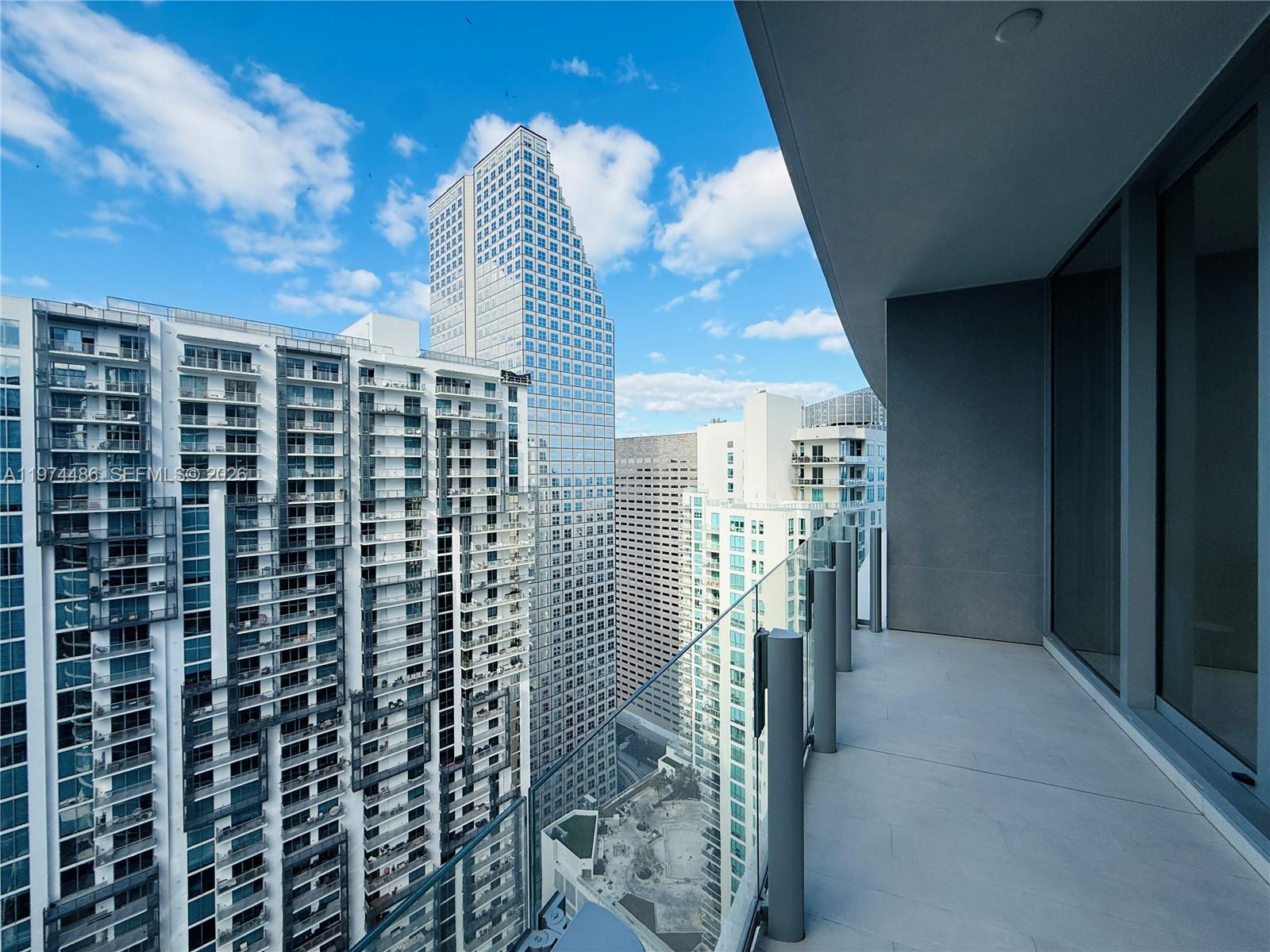 A high-rise balcony overlooks a dense urban cityscape with multiple modern glass skyscrapers — 300 Biscayne Blvd Way # 3908, Miami FL 33131, MIAMI, FL