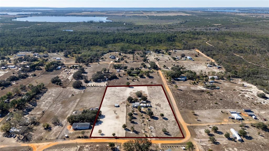 An aerial view shows a rectangular property with a house and outbuildings on sandy land — 708 FAZZINI ROAD, BABSON PARK, FL