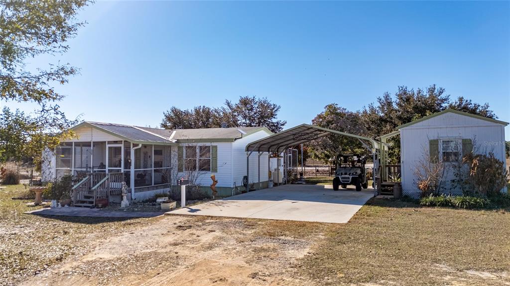 A white manufactured home with a screened porch, metal carport, and a detached shed — 708 FAZZINI ROAD, BABSON PARK, FL
