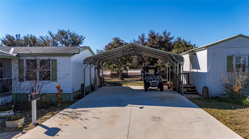 A concrete driveway leads to a metal carport between two manufactured homes under a clear sky — 708 FAZZINI ROAD, BABSON PARK, FL