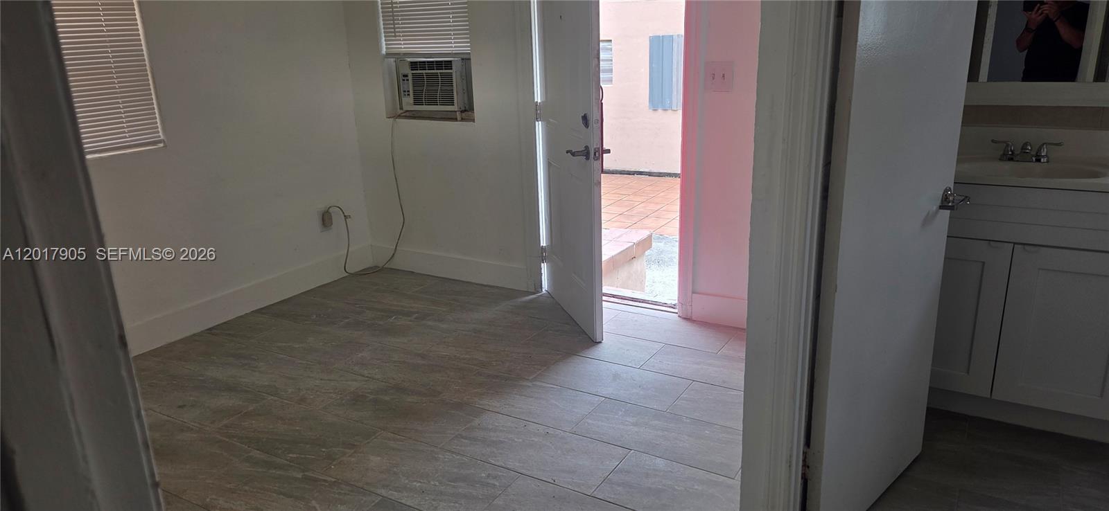 A room with tiled floors and an open door leading to an outdoor patio area — 2761 NW 16th Ter # 2, Miami FL 33125, MIAMI, FL