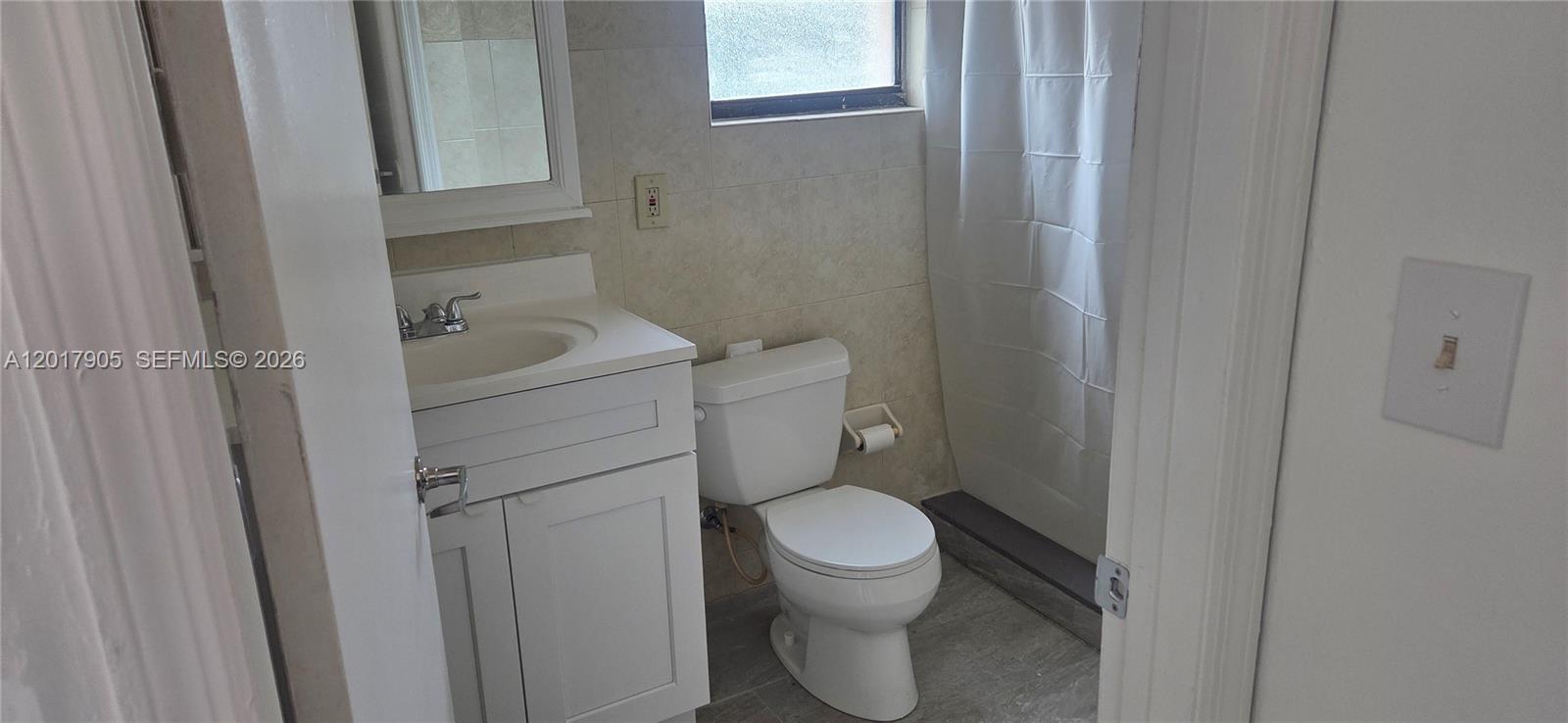 This bathroom features a white vanity, a toilet, and a shower with a curtain — 2761 NW 16th Ter # 2, Miami FL 33125, MIAMI, FL