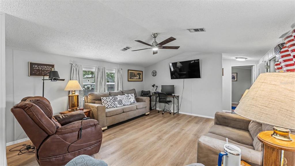 A living room features a brown recliner, a sofa, a desk, and wood-look flooring — 2690 SHINER DRIVE, LAKE WALES, FL