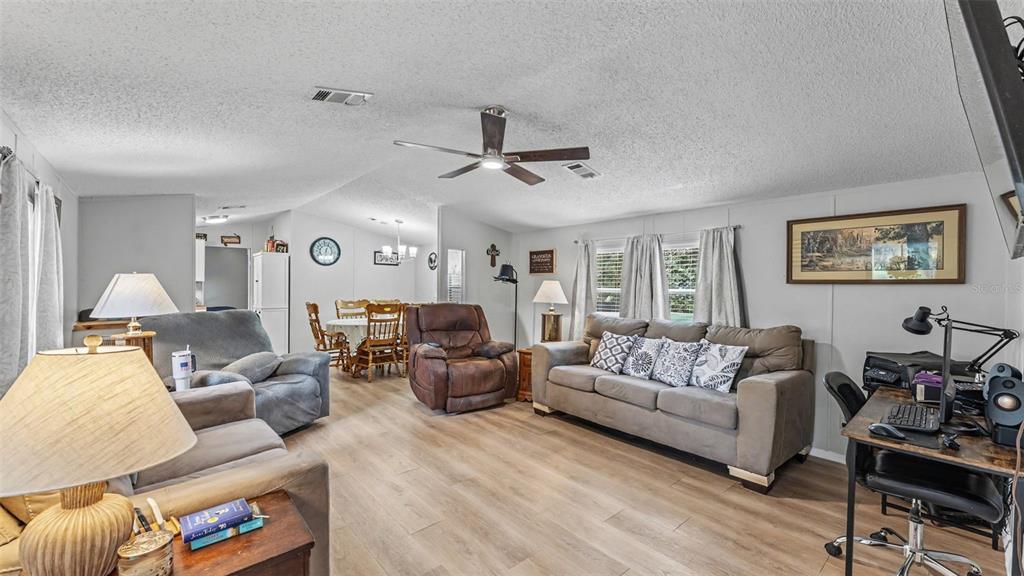 A living room with light wood-look flooring, a ceiling fan, and a dining area beyond — 2690 SHINER DRIVE, LAKE WALES, FL