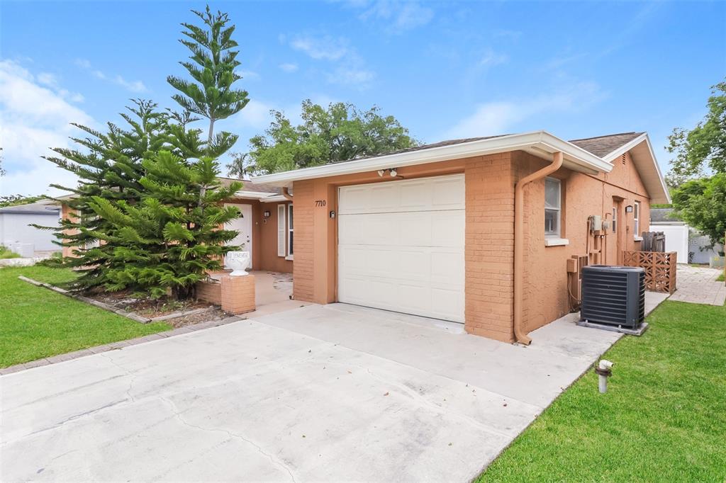 A single-story house with a brick exterior, a white garage door, and a front lawn — 7710 VENICE DRIVE, PORT RICHEY, FL