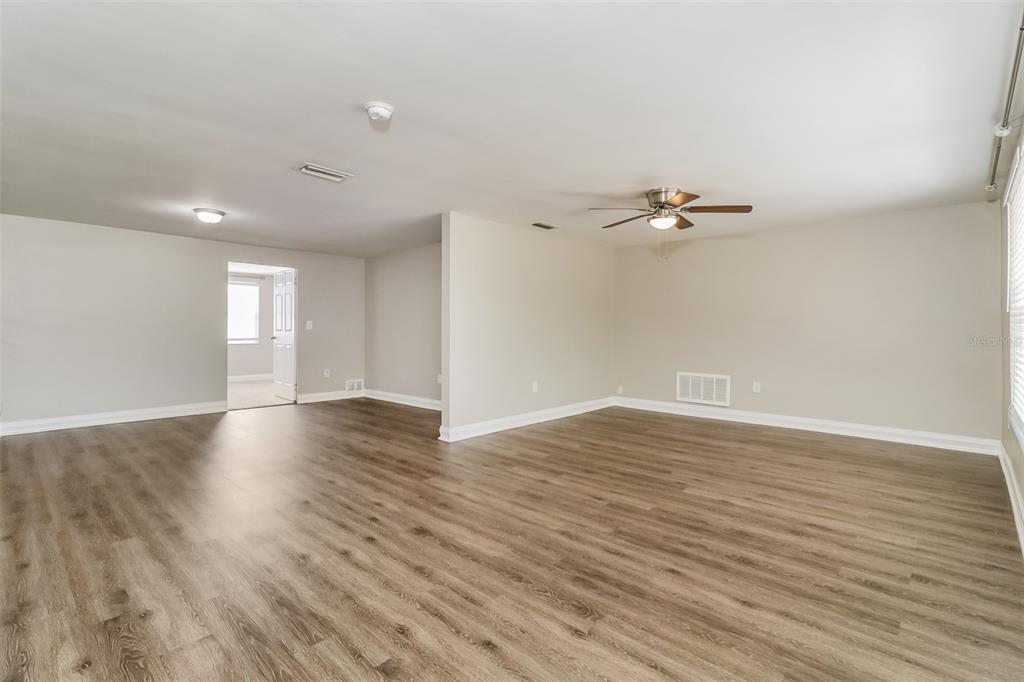 An empty room with light-colored walls, wood-look flooring, a ceiling fan, and a doorway — 7710 VENICE DRIVE, PORT RICHEY, FL