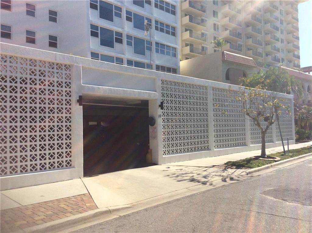 A white concrete block wall with a geometric pattern borders a parking garage entrance — 33 S GULFSTREAM AVENUE UNIT 1001, SARASOTA, FL