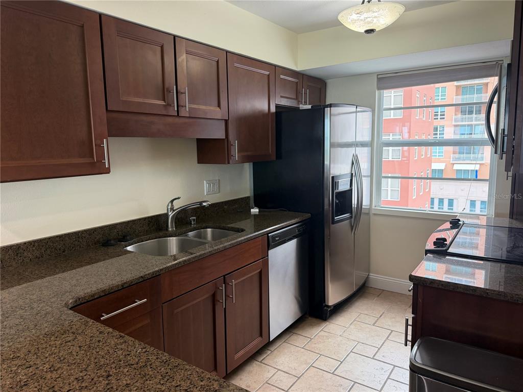 A kitchen features dark wood cabinets, granite countertops, stainless steel appliances, and a window view — 33 S GULFSTREAM AVENUE UNIT 1001, SARASOTA, FL