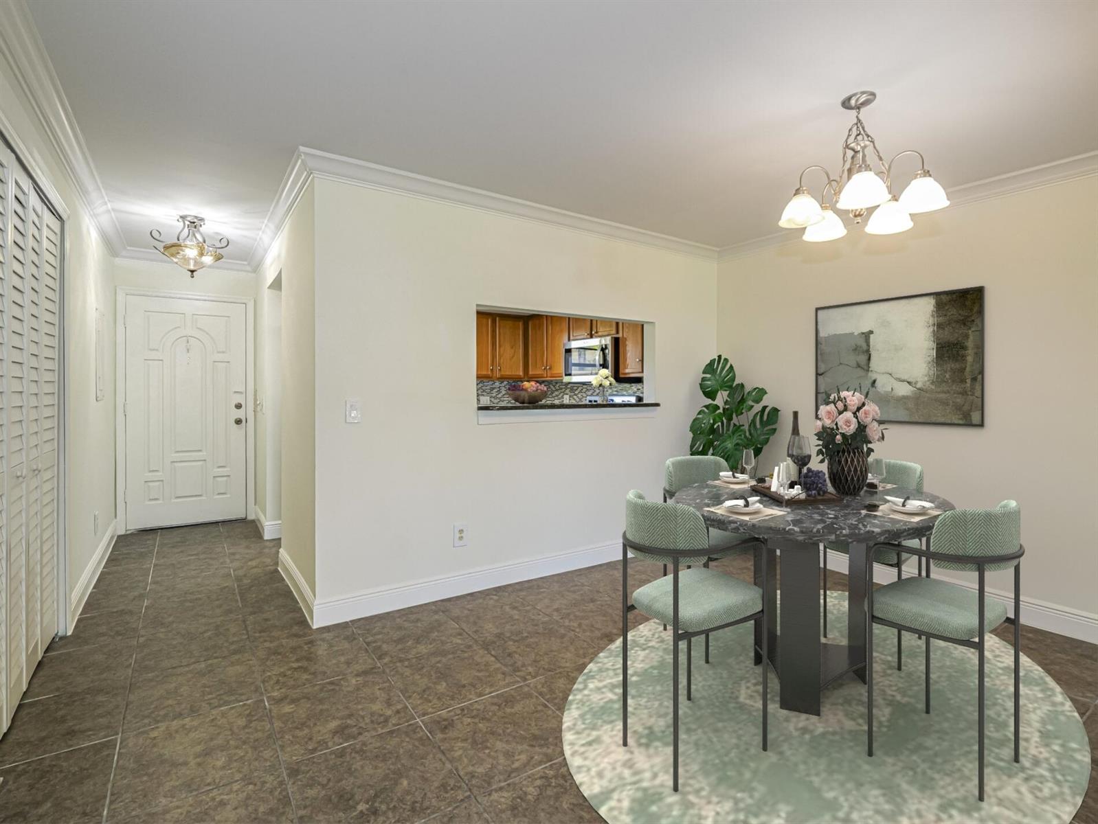 A dining area with a round marble table, light green chairs, and a kitchen pass-through window — 400 18th Street # G2, Vero Beach FL 32960, VERO BEACH, FL