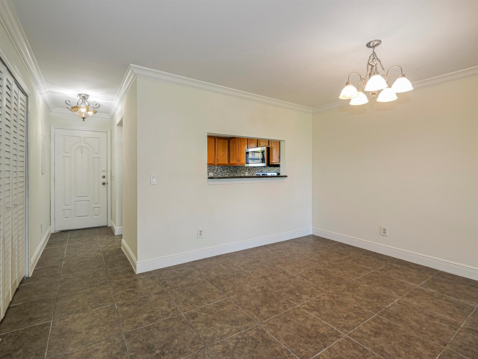 A dining area with tile flooring, a chandelier, and a pass-through window to the kitchen — 400 18th Street # G2, Vero Beach FL 32960, VERO BEACH, FL