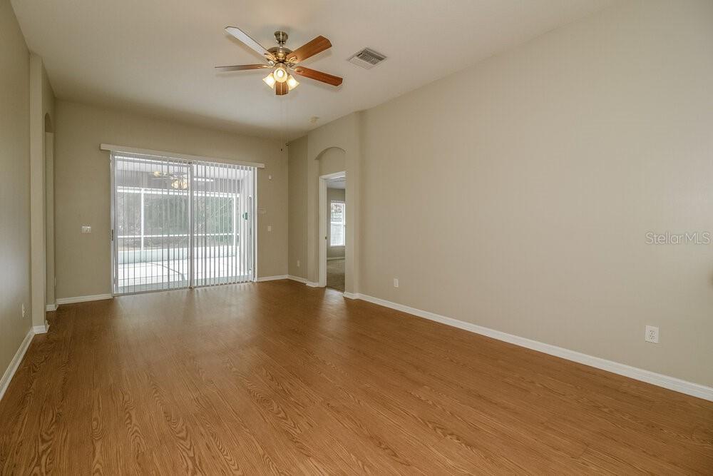 An empty living room with wood-look flooring, a ceiling fan, and sliding glass doors — 633 STRAW LAKE DRIVE, BRANDON, FL