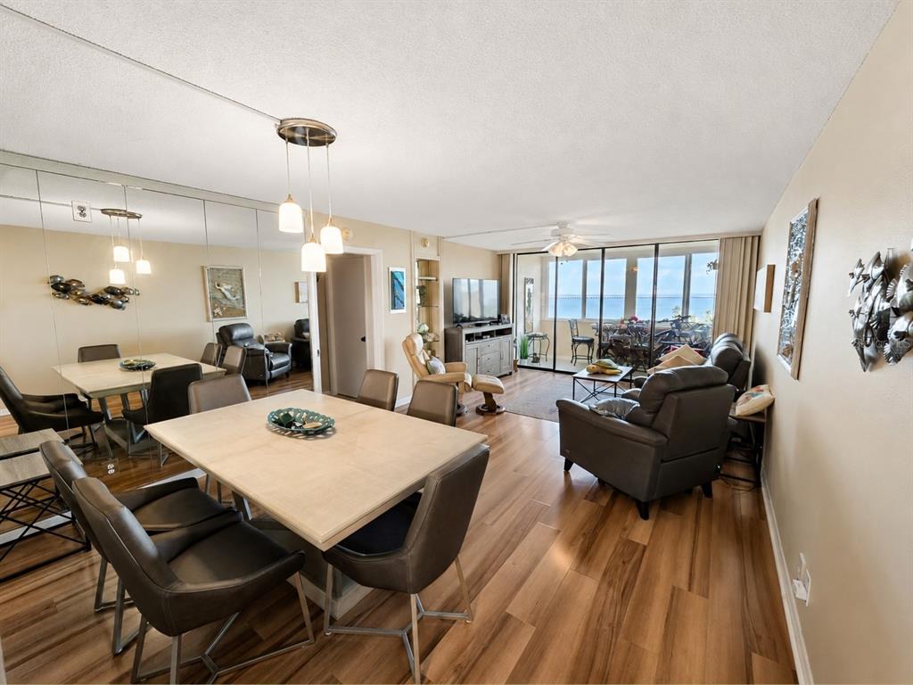 A dining and living area features wood-look flooring, a mirrored wall, and a balcony view — 2616 COVE CAY DRIVE UNIT 801, CLEARWATER, FL