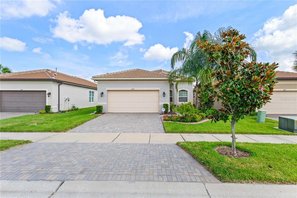 A single-story suburban house with a paved driveway, two-car garage, and a front yard — 4839 SEVILLA SHORES DRIVE, WIMAUMA, FL